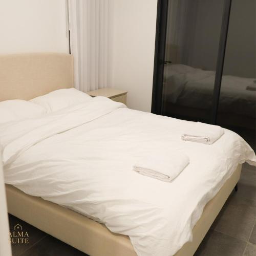 a white bed with two white towels on it at Alma suite in Ashdot Ya‘aqov