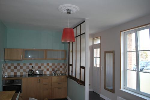 une cuisine avec une table et une lumière rouge dans l'établissement Maisonnette à Saint Valéry Sur Somme, à Saint-Valery-sur-Somme