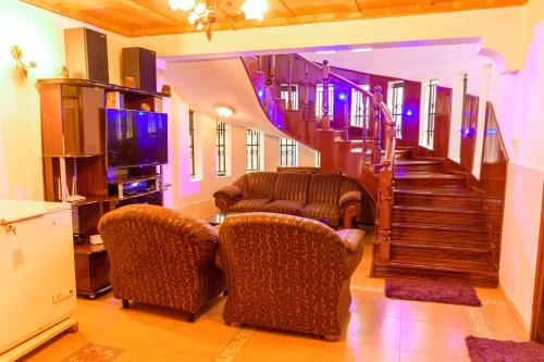 a living room with two chairs and a staircase at Havan Guest House - Eldoret in Eldoret