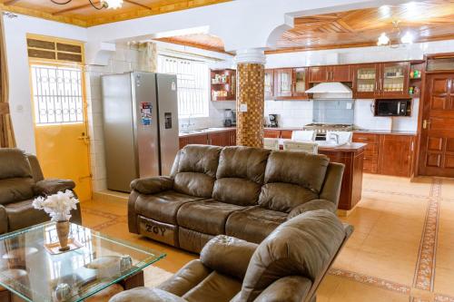 a living room with a couch and a kitchen at Havan Guest House - Eldoret in Eldoret