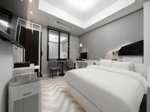 a bedroom with a large white bed and a desk at 3S HOTEL ANYANG 1st FASHION in Anyang