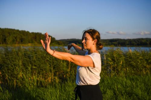 a woman standing in a field with her hands up at Uroczysko Oleśnica in Chodzież