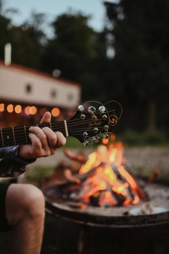 a person playing a guitar next to a fire at Uroczysko Oleśnica in Chodzież