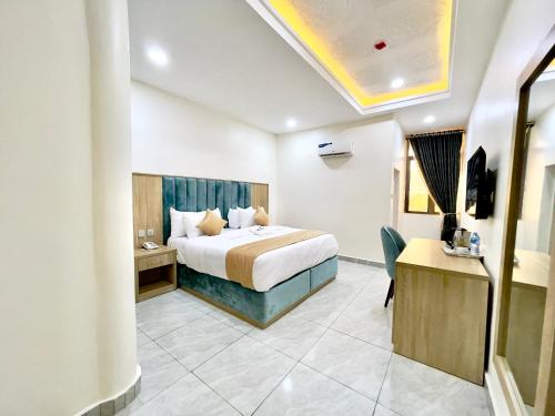 a hotel room with a bed and a desk at Uniglobe Hotel and Apartments in Gwarinpa