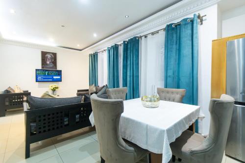 a dining room with a white table and chairs at Citadin Apart Hotel Douala in Douala