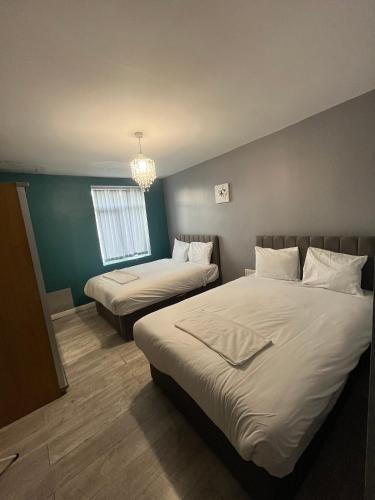 a bedroom with two beds and a chandelier at Sky's City Centre Apartments next to St James Park in Newcastle upon Tyne