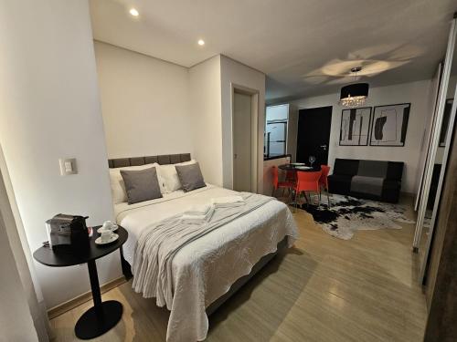 a bedroom with a bed and a table in it at Loft Centro Oktoberfest - Blumenau in Blumenau
