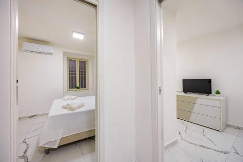 ein weißes Zimmer mit einem Bett und einem Fernseher in der Unterkunft Kiros - appartement 6 personnes - check in h24 - wifi in Lyon