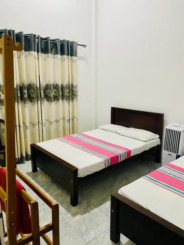 a bedroom with two beds and a curtain at VD Rest Gampola in Gampola
