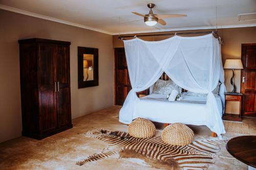 a bedroom with a bed with a mosquito net at African Safari Lodge in Grahamstown