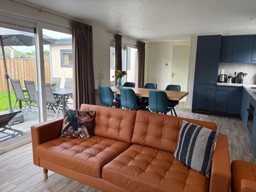 a living room with a brown couch and a table at Chalet Pareloester - Ouddorp in Ouddorp