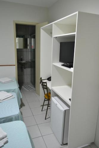 a room with a bed and a desk with a television at Hotel Itapoã in Teresina