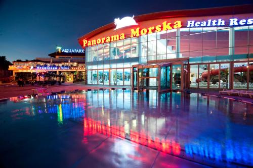 a hospital building with a reflecting pool in front of it at Aquapark Health Resort & Medical SPA Panorama Morska All Inclusive in Jarosławiec