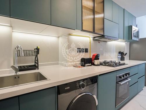 a kitchen with a sink and a washing machine at Royalton - Private Pool Luxe Studio in Dubai in Dubai
