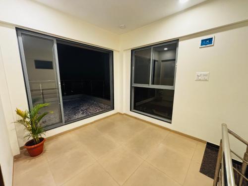 a room with two large windows with a potted plant at City Of Music - Nirvana in Pali