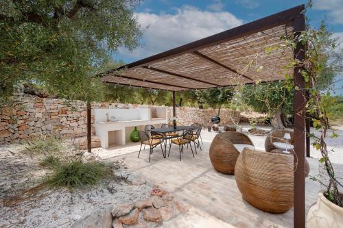 a patio with a table and chairs under a pavilion at Trulli di Titti - Luxury Country House in Castellana Grotte