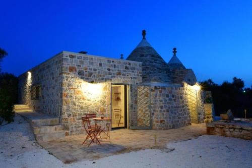 a stone building with a table and chairs at night at Trulli di Titti - Luxury Country House in Castellana Grotte