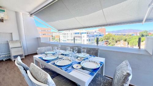 a dining room with a table and chairs and a window at Magnífico Ático 4 hab frente a la playa con piscinas parking incluido por keywise in Fuengirola