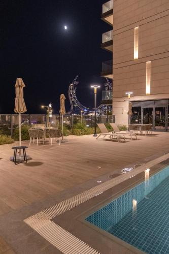 a pool with tables and umbrellas in front of a building at Lusail House in Doha