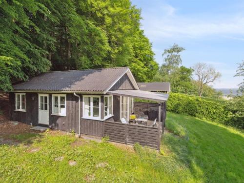 a small house on a grassy hill with trees at Holiday Home Ginne - 100m to the inlet by Interhome in Løgstrup