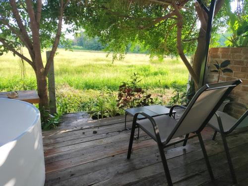 a table and chairs on a wooden deck with a field at Minimal house in Doi Saket