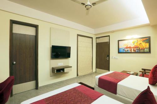 a hotel room with a bed and a flat screen tv at Hotel Cardinal Express Oxmo Delhi Airport in New Delhi