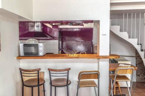 a kitchen with a counter with chairs and a microwave at Maison de bourg Cébazat in Cébazat