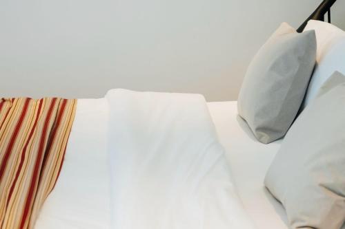 a bed with white sheets and pillows on it at Artifact Apart Hotel in Tbilisi City