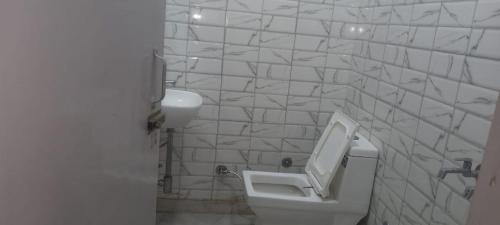 a white bathroom with a urinal and a sink at Hotel Saffron in Meerut