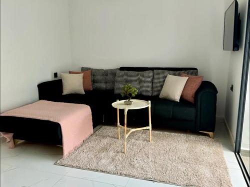 a living room with a black couch and a table at Sabir Hadaj in Kenitra