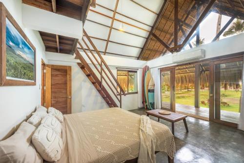 a bedroom with a large bed and large windows at Libertad Surf Villa in General Luna