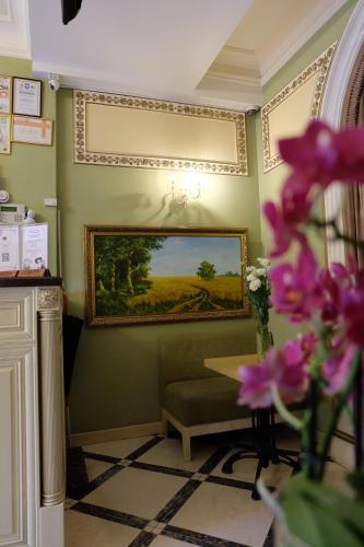 a room with a painting on the wall and a table and flowers at Hotel Lavilia in Kyiv
