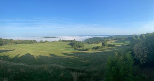an aerial view of a green field with trees and clouds at S'évader vers l'horizon 6pers, calme, wifi in Chalvignac