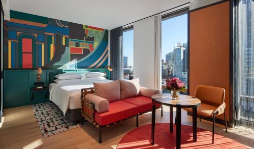 a hotel room with a bed and a red chair at Caption By Hyatt Central Sydney in Sydney
