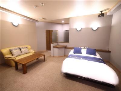 a bedroom with a bed and a couch and a table at ホテルピースプラス in Kamisu