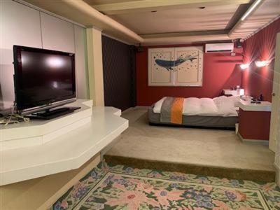 a room with a television on a counter with a bed at ホテルピースプラス in Kamisu