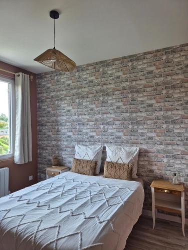 a bedroom with a brick wall and a large bed at Le Millésime in Eu