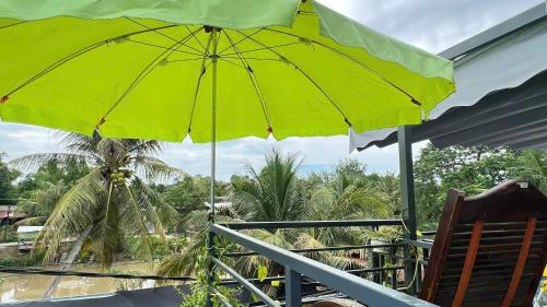 a green umbrella sitting on top of a balcony at HOMESTAY Hoàng GIa in Ấp Ông Tú