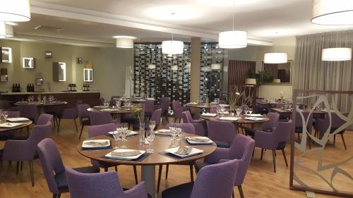 a dining room with tables and purple chairs at Threeland Hotel in Pétange