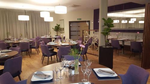 a dining room with tables and purple chairs at Threeland Hotel in Pétange
