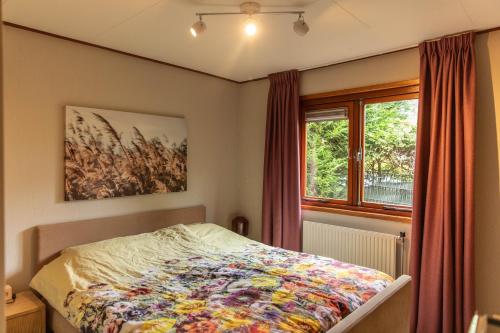 a bedroom with a bed with a colorful quilt on it at Chalet Fuut in Erm