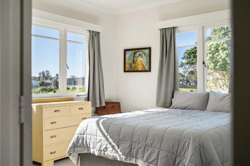una camera con letto, cassettiera e finestre di Coastal Escape - Waihi Beach Holiday Home a Waihi Beach