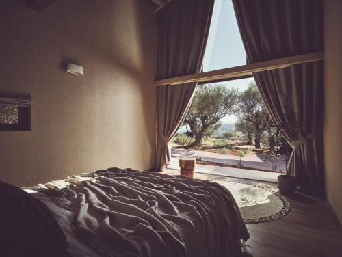 a bedroom with a bed and a large window at Prosilio olive tree houses in Tsilivi