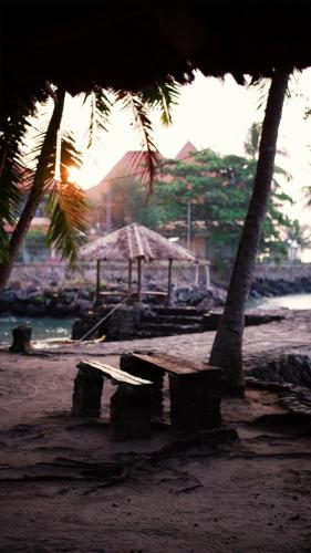 a beach with two palm trees and an umbrella at Pondok Kalimaya in Serang