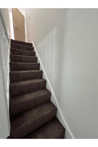 a staircase in a house with brown carpeted stairs at Home Sweet Home in Dagenham Dock