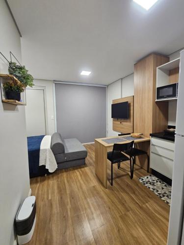 a small room with a bed and a desk with a tv at Studio Cuiabá in Cuiabá