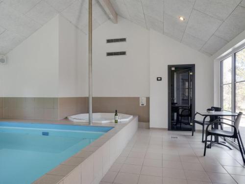 a swimming pool in a room with a table and chairs at Holiday Home Lova - 600m from the sea by Interhome in Blåvand
