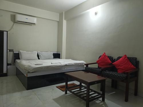 a bedroom with a bed and a couch and a table at Hotel Naman in Patna