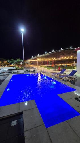 a blue swimming pool at night with a street light at شاليهات Chalets in Būbādī