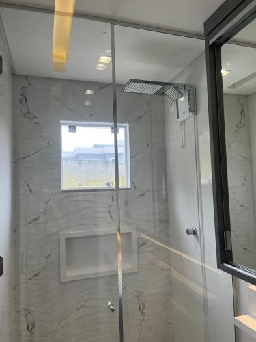 a shower with a glass door and a window at Studio aconchegante e tranquilo! Perto de tudo! in Indaial